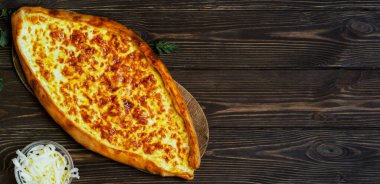 Peynirli Türk ekmeği (pide). Karanlık ahşap masada Kasarli pide. Fotokopi alanı olan düz bir yer. Geleneksel Türk pizzası.