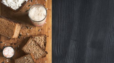 Leavened bread, whole grain rye bread with pumpkin and sunflower seeds. Leaven starter on table. Authentic sourdough bread, organic bio product. Top view with copy space, slices of bread board