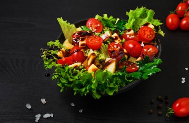 Marullu domates salatası, keçi peyniri, taze sebze, susam tohumu ve siyah ahşap masada zeytinyağı. Yakın plan. Sağlıklı sağlıklı yiyecekler.