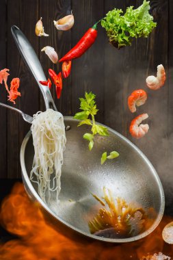 Uçan tava malzemeleri - karides, sebze, marul, soya sosu ve baharatlar. Yakın plan, karidesli erişte pişirme işlemi. Çin mutfağı ya da doğu yemekleri için açık ateşte pişirilen tarifler.