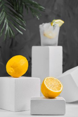 Limonlar ve limonata bardağı gri nötr arka planda, limonlu minimalist konsept. Yakın plan, seçici odaklanma. Geometrik biçimler, kopyalama alanı olan arkaplan