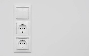 İki beyaz plastik elektrik prizi bloğu ve beyaz alçılı bir duvarda izole edilmiş bir anahtar. Avrupa 'nın elektrik prizi kopyalama alanını kapattı