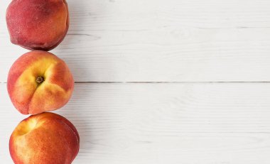 Taze sulu şeftaliler, beyaz ahşap bir masanın üzerinde. Manzara, pankart fikri ya da çiftlikten taze meyve reklamı.