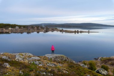 Kuzey Kutup Dairesi yakınlarındaki Beyaz Deniz kıyısındaki bir gezginin silueti. Körfezin karşısındaki Kovda kırsal köyünün çarpıcı manzarası, en eski yerleşim yerlerinden biri..