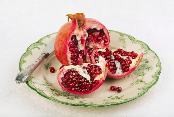 Opened red pomegranate on a rustic plate — Stock Photo, Image