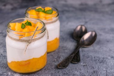 Kavanozda mango püresi olan Yunan yoğurdu. Yakın plan..