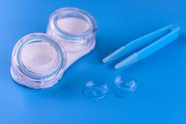 Container for contact lenses and lenses on a blue background.Close-up.