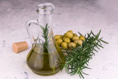 Beyaz arka planda zeytinyağı sürahisi ve biberiye dalları.