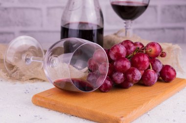 Tahta bir tahtanın üzerinde bir bardak kırmızı şarap ve bir demet üzüm. Yakın plan..