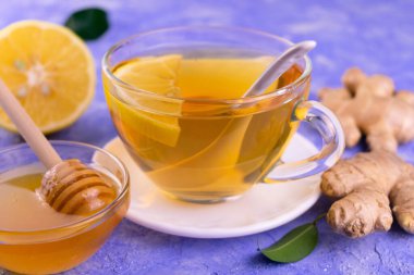 Açık mavi arka planda zencefilli bal ve limonlu bir fincan çay. Yakın plan..