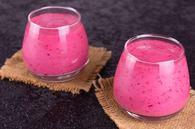 Siyah arka planda göbekli bardaklarda meyveli içecekler..