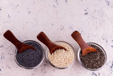 Üç kase sağlıklı haşhaş, chia ve susam tohumu. Boşluğu kopyala.