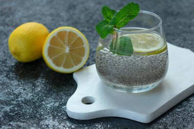 Zayıflatıcı içecek. Siyah arka planda Chia tohumlu ve limonlu cam su..