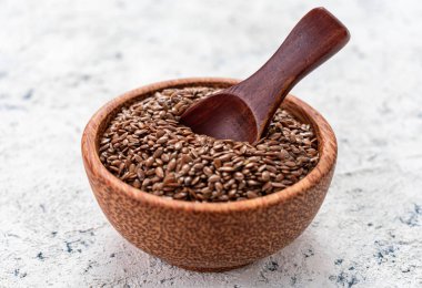 Sağlıklı keten tohumları beyaz arka planda ahşap bir kasede.