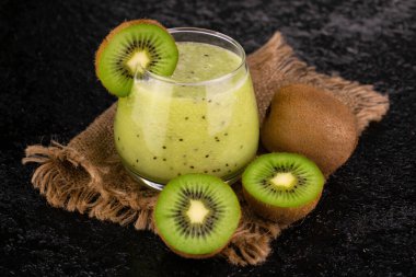 Siyah arka planda bir bardak taze kivi püresi..