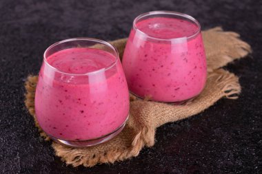 Siyah arka planda iki bardak çilekli meyve suyu..