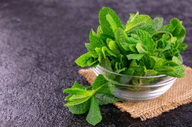 Siyah arka planda cam bir kasede taze nane. Boşluğu kopyala.