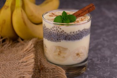 Gri arka planda tarçınlı muzlu yoğurt. Yakın plan..