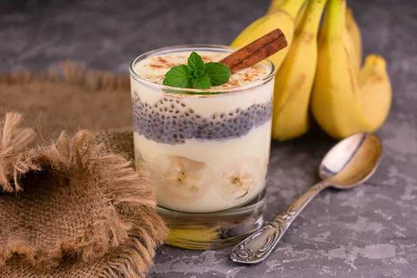 Banana yogurt with cinnamon in a glass on a gray background. Close-up.