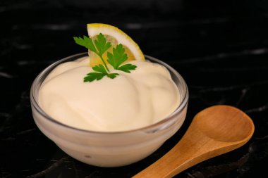 Siyah arka planda cam bir kasede mayonez sosu. Yakın plan..