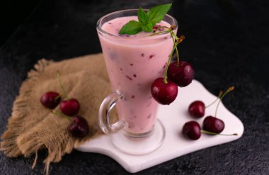 Siyah arka planda uzun bir bardakta vişneli buzlu içecek. Yakın plan..