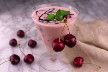 Beyaz mermer arka planda bir bardakta vişneli ve ekşi smoothie. Yakın plan..
