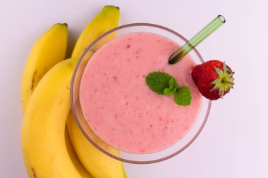 Beyaz arka planda çilekli ve muzlu smoothie. Yukarıdan görüntüle.