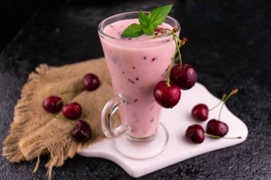 Siyah arka planda, uzun bardaklarda taze kirazlı meyve suları. Seçici odak.