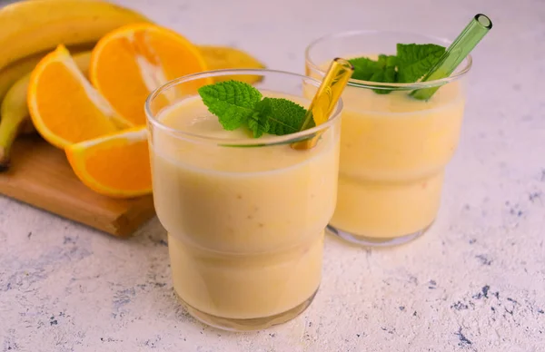 Due Bicchieri Frullato Banana Arancione Con Una Foglia Menta Uno — Foto Stock