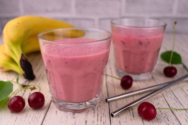 Taze böğürtlenli ve beyaz ahşap arka planda muzlu pembe vişneli içecekler..