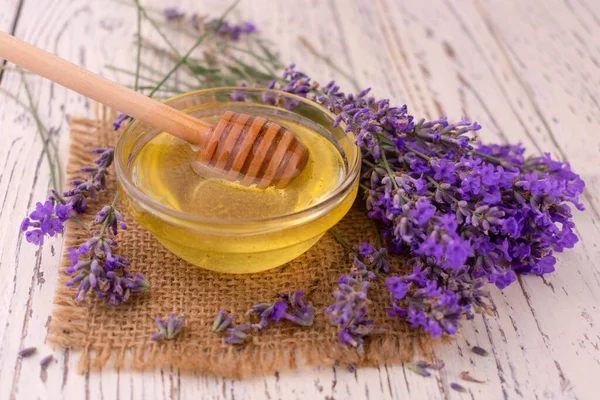 Bowl with fresh lavender honey on a white wooden background.