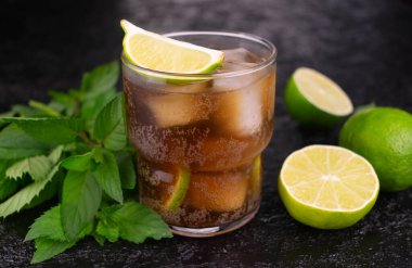 Siyah zemin üzerinde limon ve kahverengi rom ile Küba Libre kokteyli..