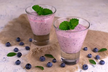 Beyaz bir masada iki bardak sağlıklı yabanmersinli içecek..