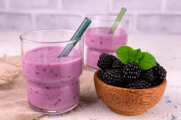 Beyaz arka planda iki bardak böğürtlen suyu..