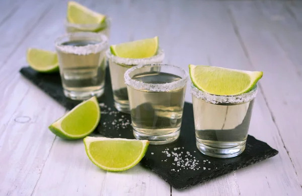 Mexican tequila with lime and salt on a white wooden rustic background.