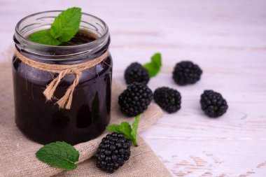 Beyaz ahşap arka planda bir kavanozda Blackberry reçeli.