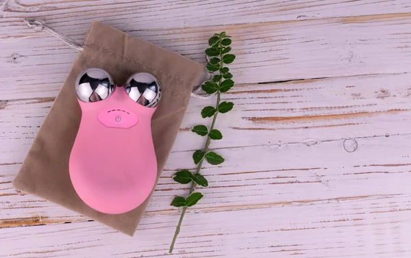 Beyaz ahşap arka planda mikro akım yüz masajı. Boşluğu kopyala.