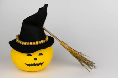 Siyah cadı şapkalı balkabağı ve gri arka planda süpürge sapı. Cadılar Bayramı konsepti Boşluğu kopyala.