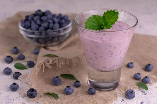 Dokulu bir peçetede, bardakta yaban mersinli smoothie..