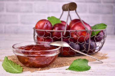 Cam bir kasede, bir sepet eriğin arka planına karşı ev yapımı erik reçeli. Erik reçeli.