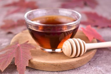 Ahşap tepside küçük bir cam kasede akçaağaç şurubu. Yakın plan..