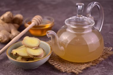 Gri arka planda şeffaf bir çaydanlıkta zencefil çayı.