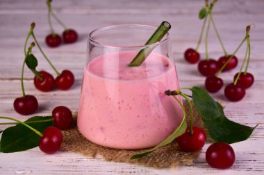 Beyaz ahşap arka planda, bardaktaki sağlıklı vişneli smoothie. Yakın plan..