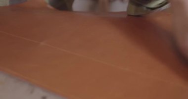 Tanner 'lar deri ürünü yapmadan önce deri çarşafı düzeltirler.