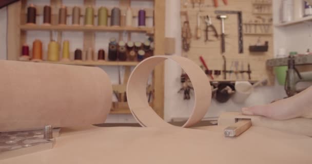 Ambachtelijke snijdt een lange strook van een vel leer om een riem te maken — Stockvideo