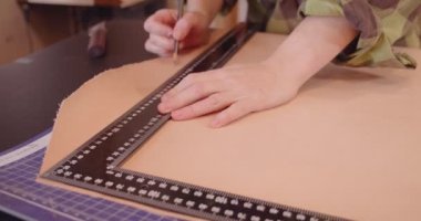 Bir bronzlaştırıcı, büyük bir deri tabakasını ve bir cetvelle çanta yapmak için ölçer.