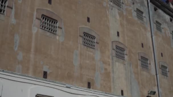 Okna celi więziennych z metalowymi kratami, widok z ulicy. — Wideo stockowe
