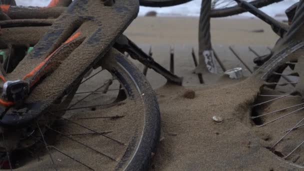 Bicicletas rotas en la playa, cubiertas de arena durante una tormenta — Vídeo de stock