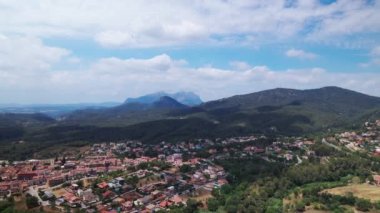 Güneşli bir havada küçük bir Avrupa kasabasının üzerinden yüksek dağlara doğru uçmak