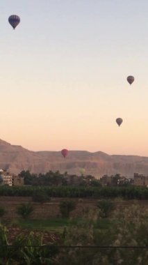 Sıcak hava balonları gün doğumunda Luxor 'da çölün üzerinde süzülüyor..
